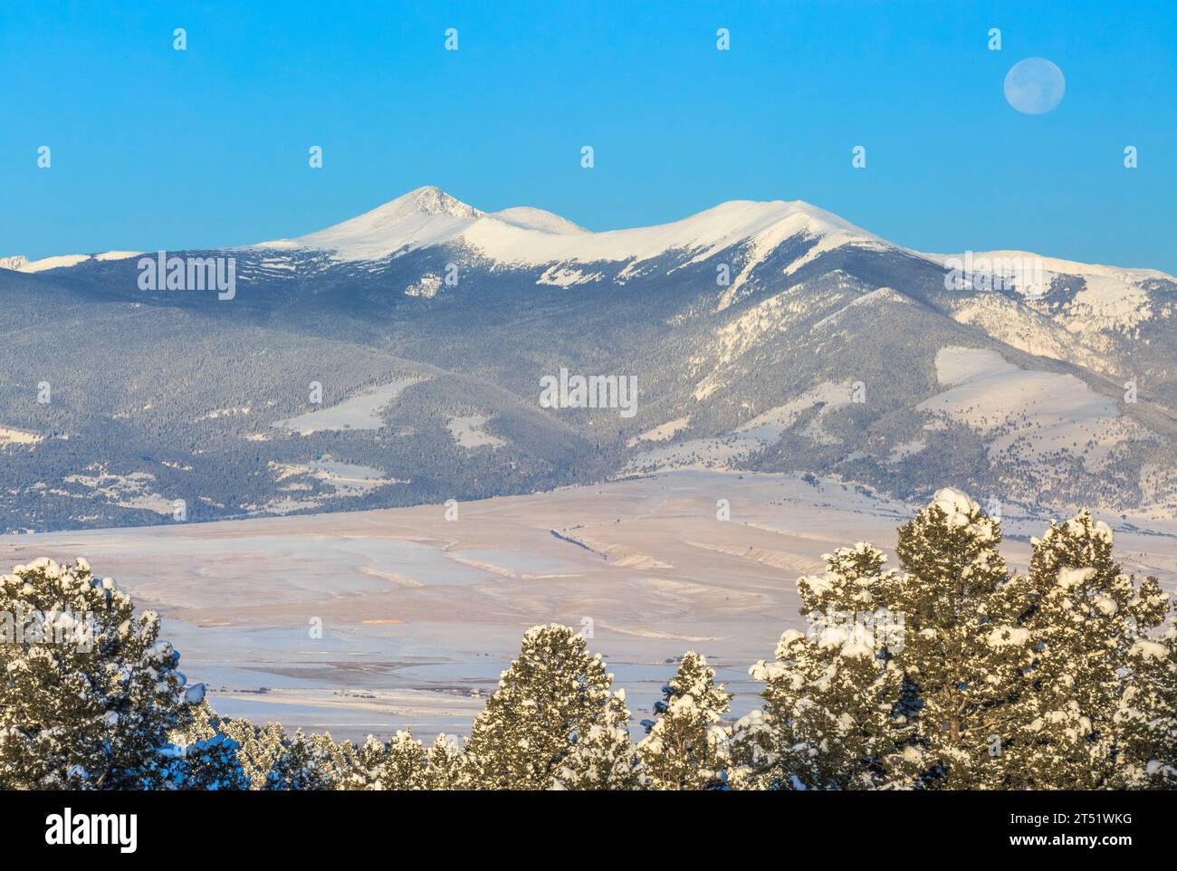 full moon settiing over the flint creek range in winter near deer lodge ...