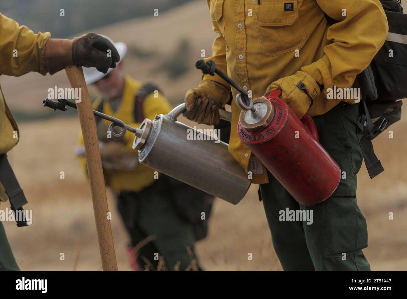 Firefighter holds drip torches before a control burn Stock Photo
