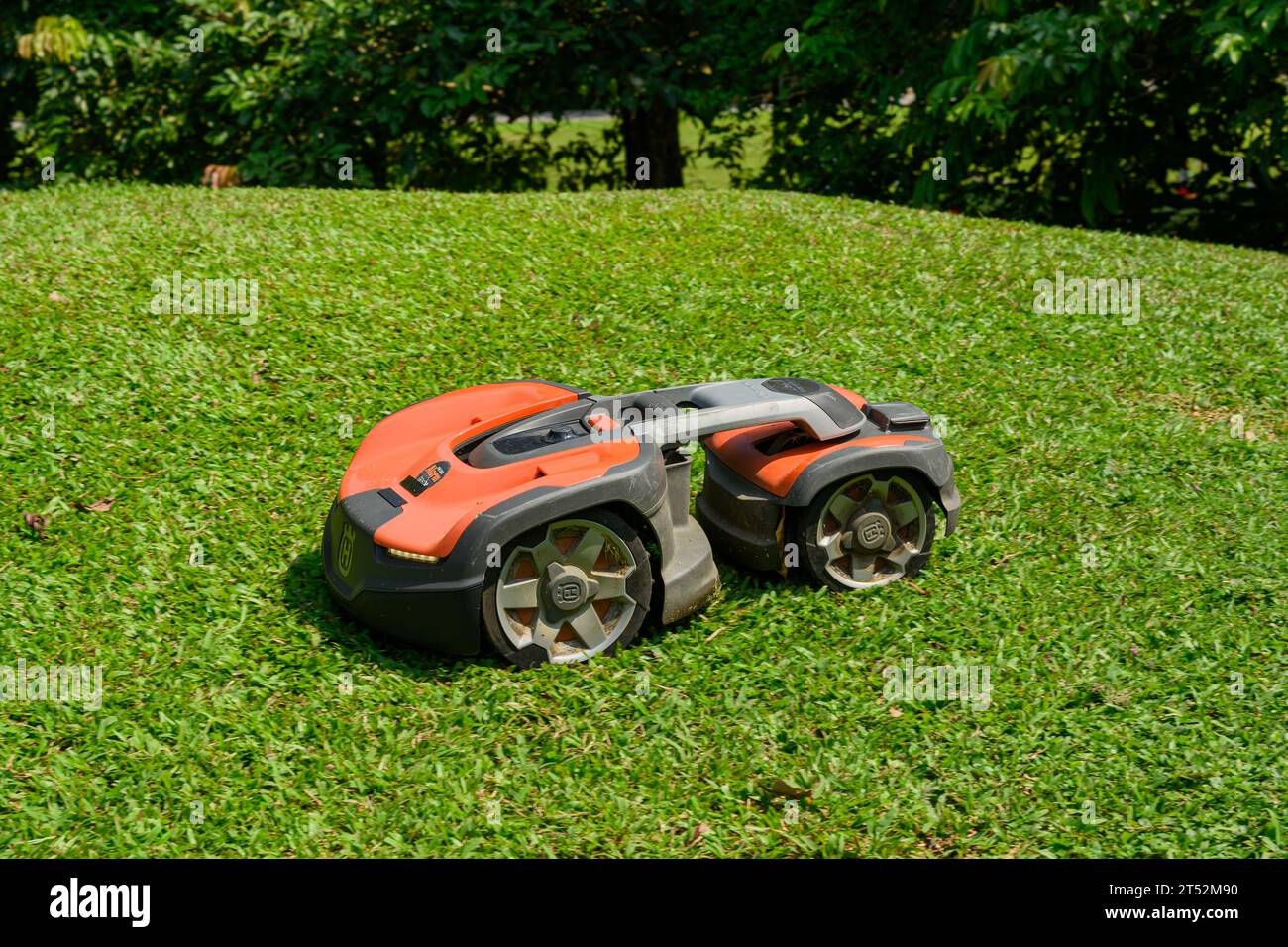 A Husqvarna Robotic Lawn Mower in action on a sunny day Stock Photo
