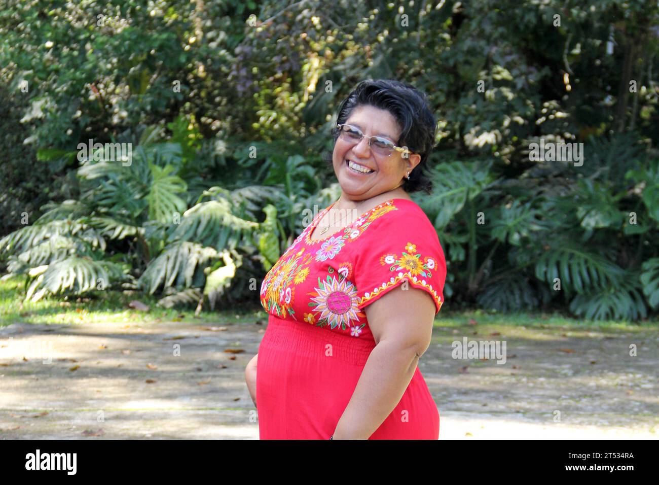 Overweight brunette Latina adult woman in her 50s is happy and proud of her roots wearing traditional Mexican embroidered dress Stock Photo