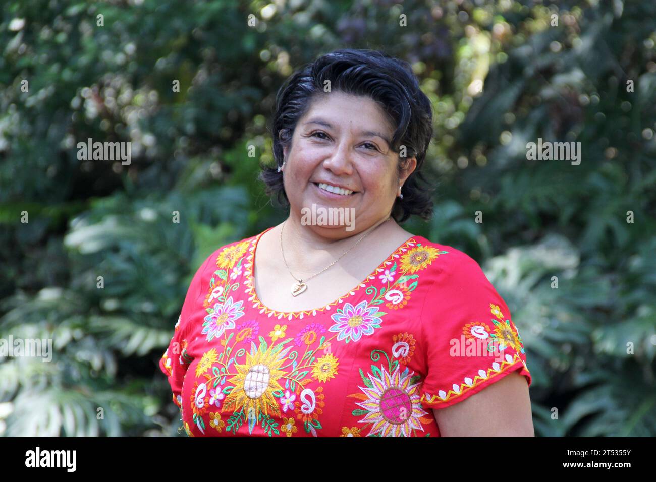 Overweight brunette Latina adult woman in her 50s is happy and proud of her roots wearing traditional Mexican embroidered dress Stock Photo