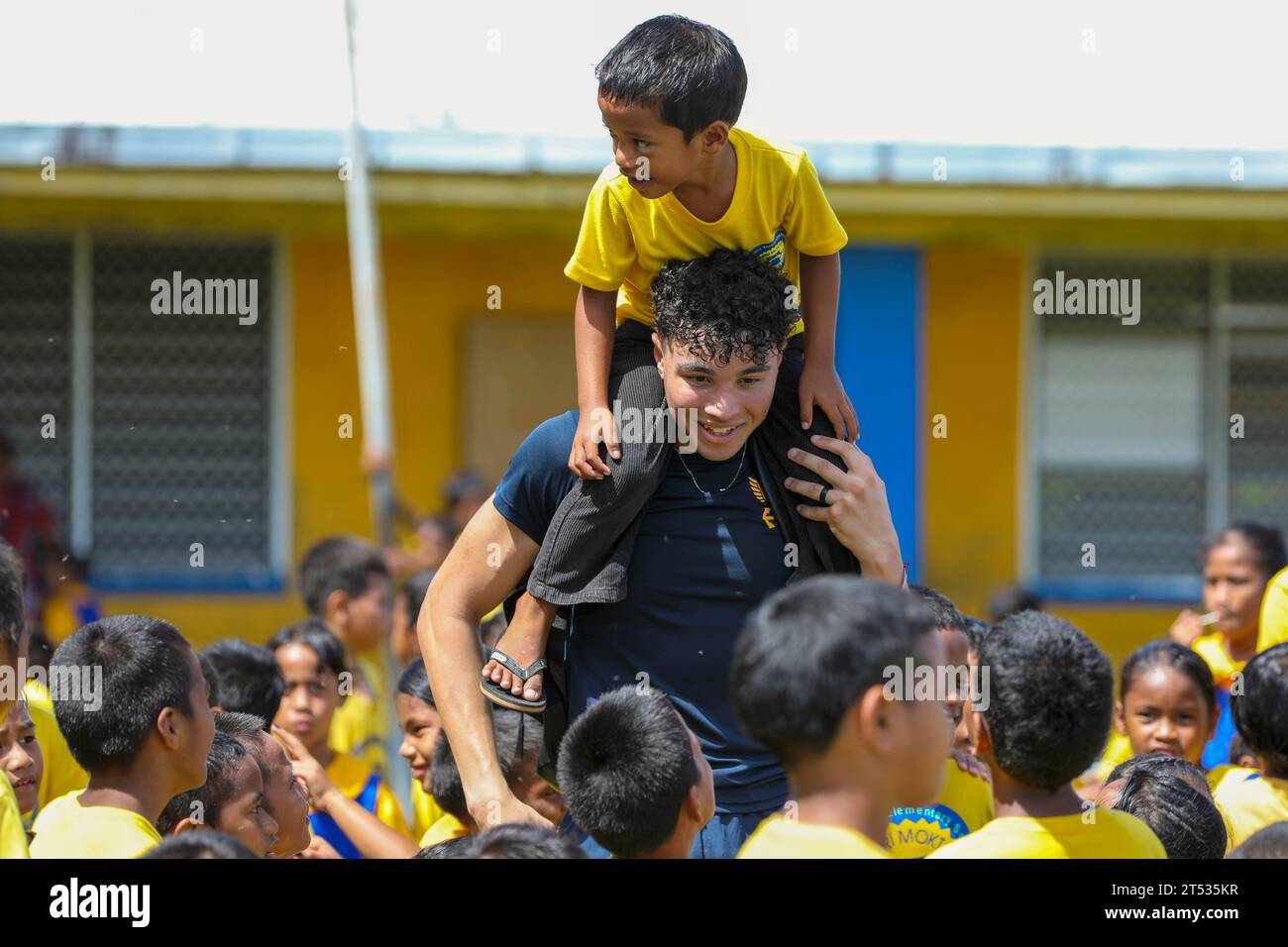 Majuro, Marshall Islands. 31st Oct, 2023. U.S. Navy Hospitalman Julian Dawkins, from Merced, California, gives a student a ride on his shoulders during a U.S. Navy Pacific Fleet and Royal Australian Navy Band concert and sports day at Delap Elementary School in Majuro, Republic of the Marshall Islands, during Pacific Partnership 2024-1 Nov. 1, 2023. Pacific Partnership, now in its 19th iteration, is the largest multinational humanitarian assistance and disaster relief preparedness mission conducted in the Indo-Pacific and works to enhance regional interoperability and disaster response cap Stock Photo