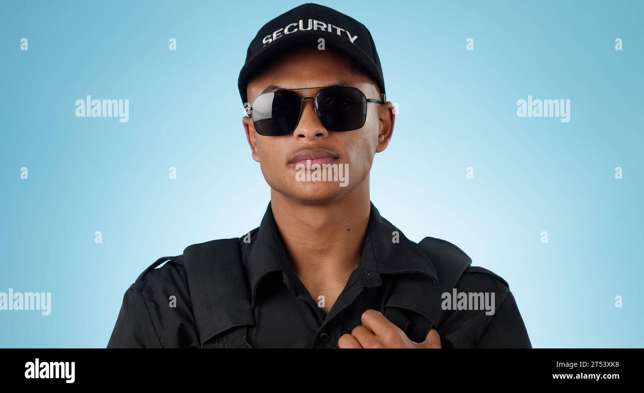 Security guard, portrait and man in studio with glasses for surveillance, justice and law enforcement on blue background. Serious bodyguard for crime Stock Photo