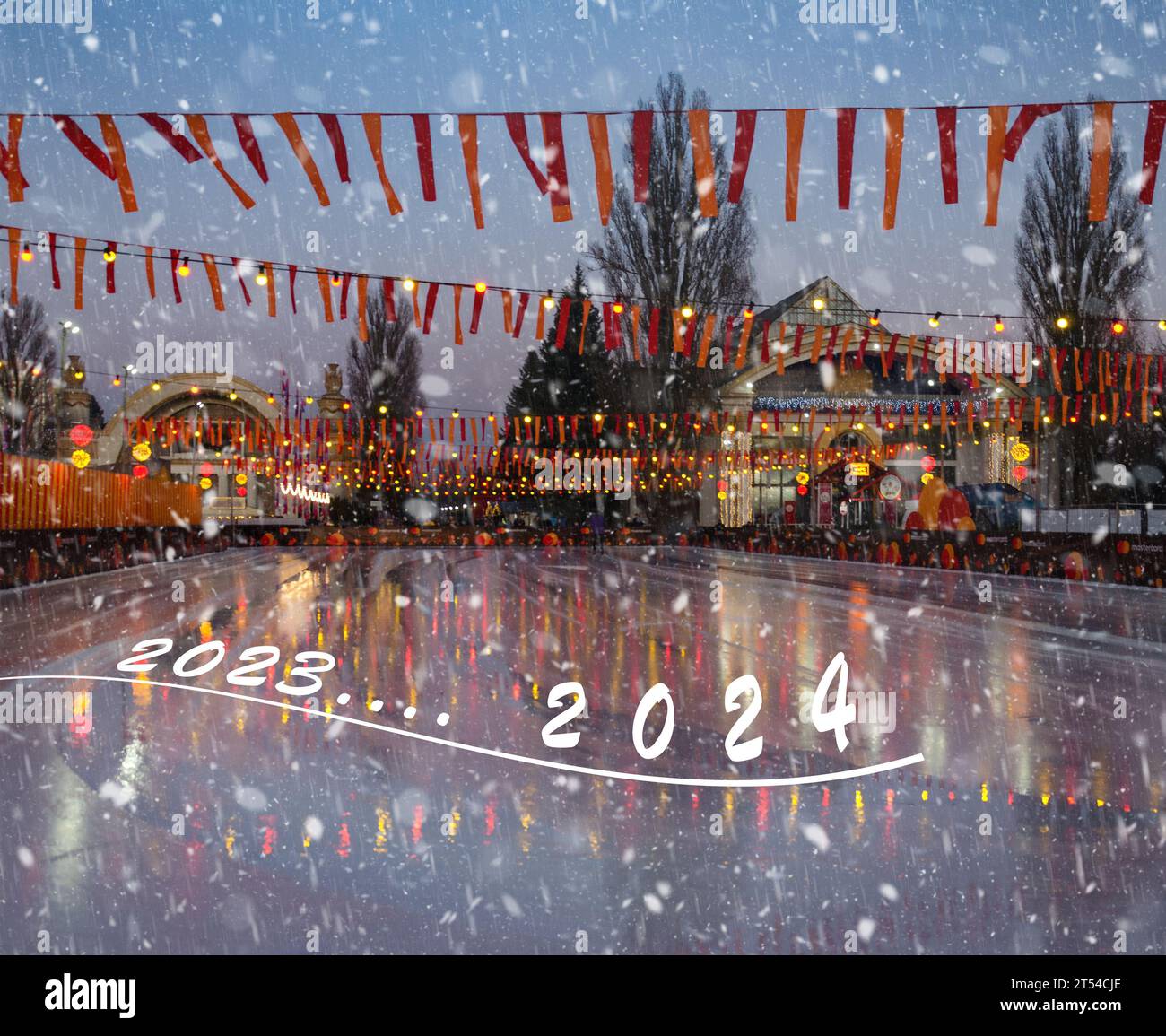 The inscription 2023-2024 on the skating rink decorated with bright flags, on a snowy evening. Stock Photo
