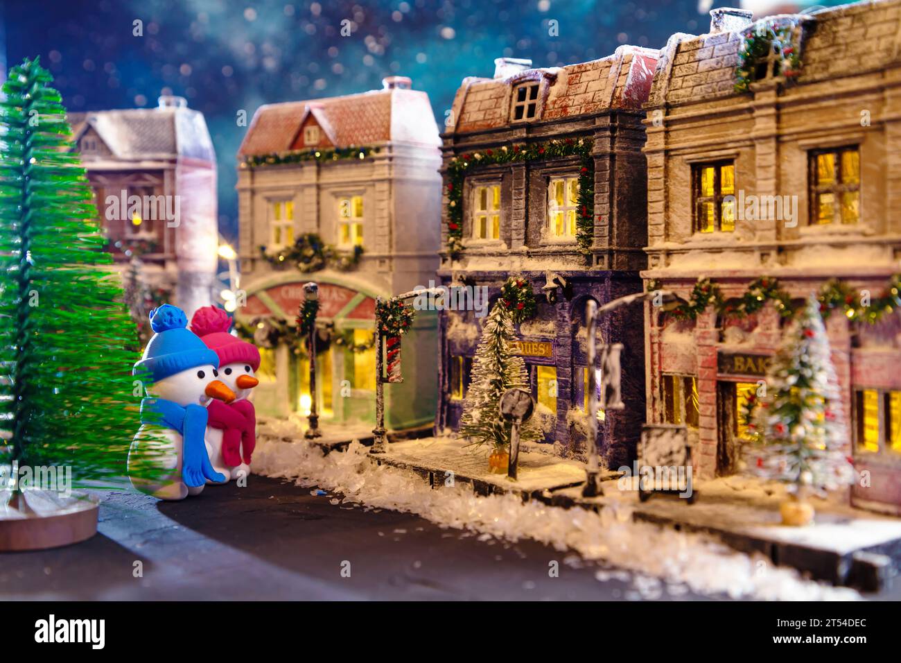 Snowmen on a nightly snow-covered street decorated for Christmas. Homemade decorated toy houses. All elements of the image are made and drawn by hand. Stock Photo