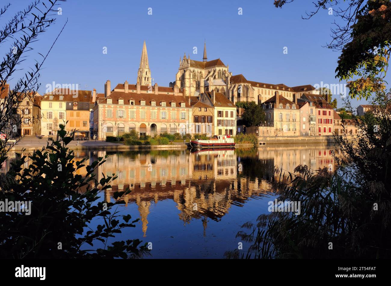 Auxerre: Abbey Saint-Germain and period buildings glowing gold with reflections in the River Yonne soon after sunrise in Auxerre, Burgundy Stock Photo