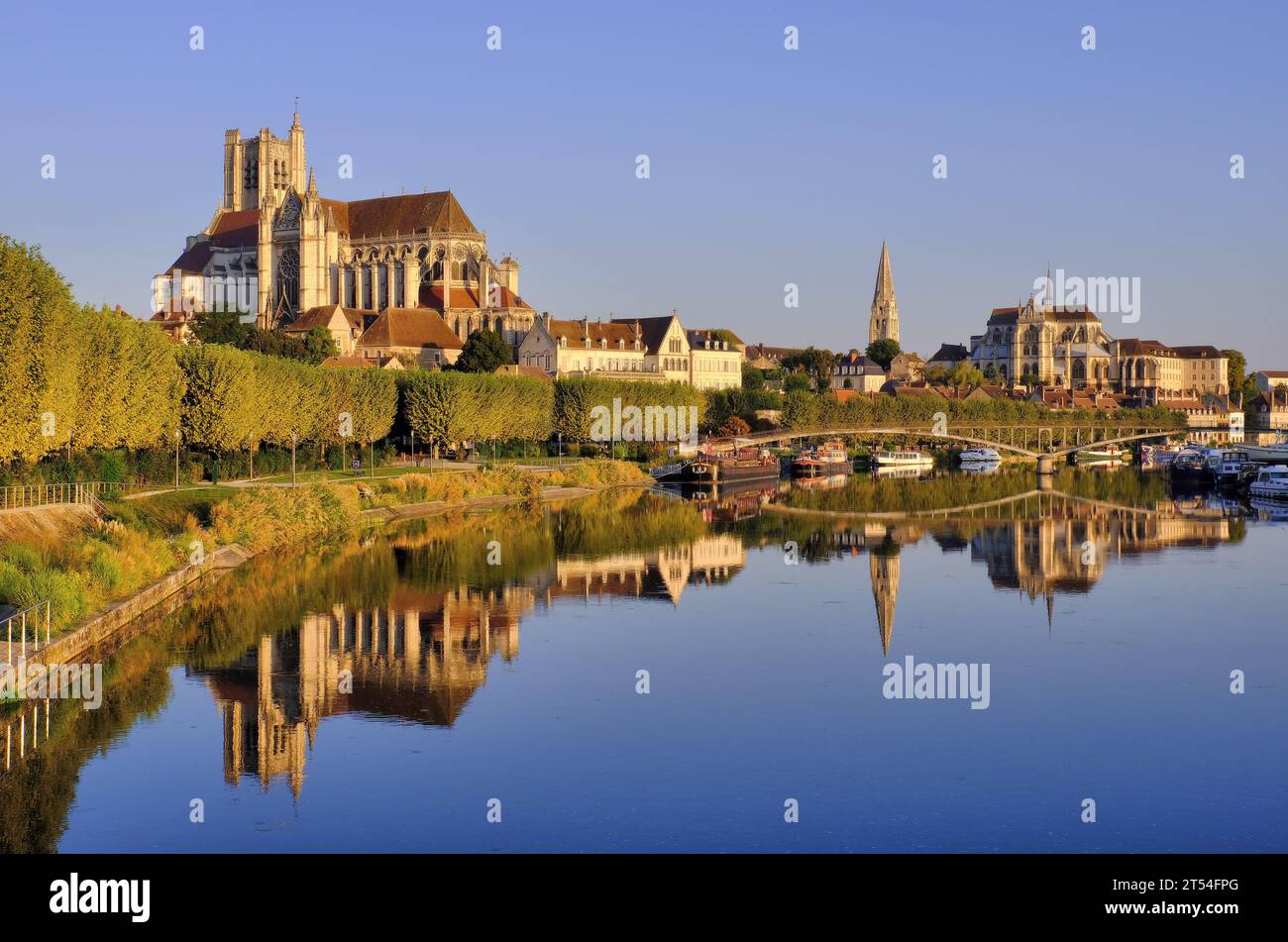 Auxerre: Cathedral Saint Etienne, Abbey Saint-Germain and boats glowing gold soon after sunrise with mirror reflections in River Yonne, Burgundy Stock Photo