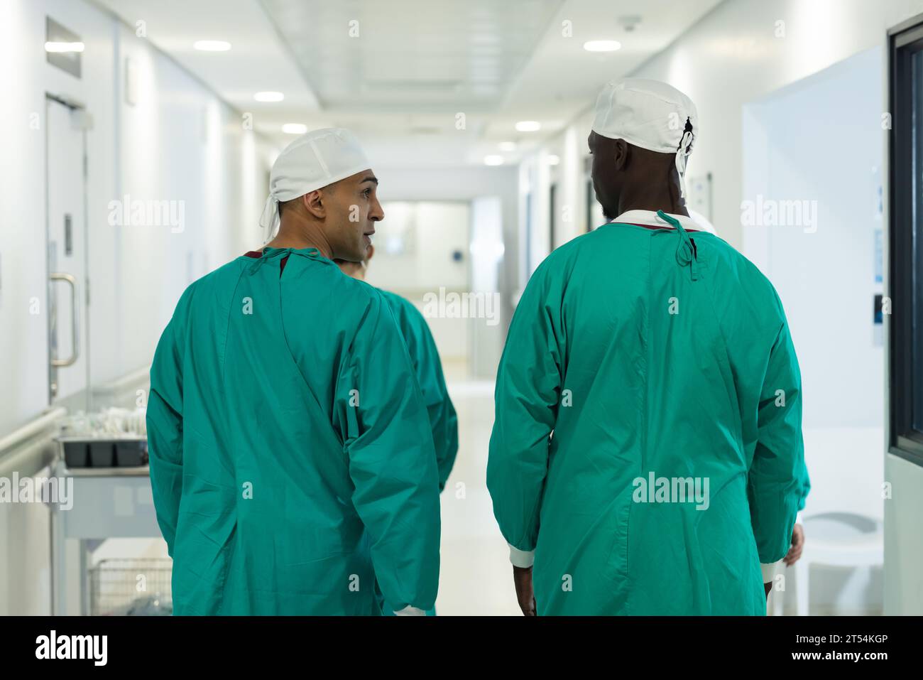 Diverse male surgeons wearing surgical gowns walking in corridor at