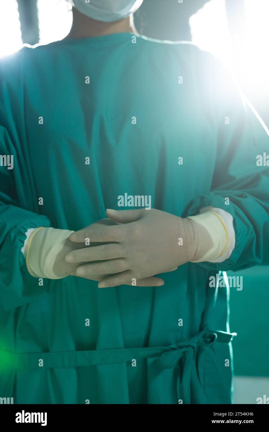 Midsection of asian female surgeon wearing surgical gown in operating theatre at hospital Stock Photo