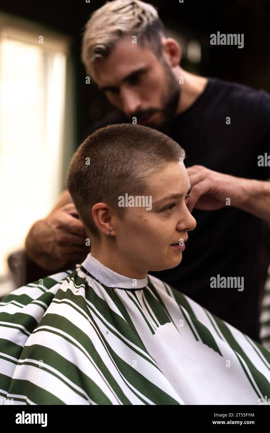 A stylist cuts a woman's hair short with a clipper. Stock Photo