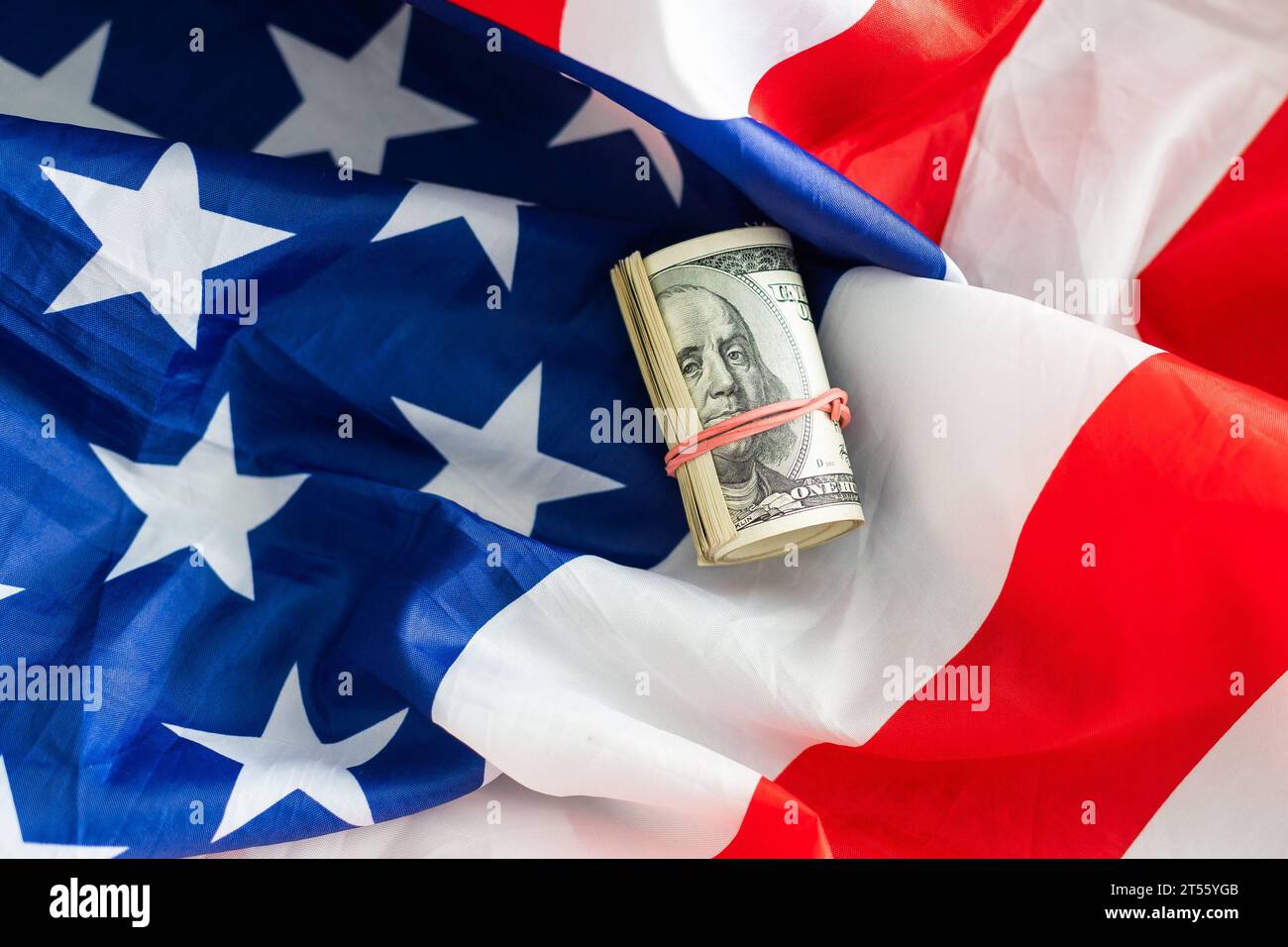 American striped flag and a stack of one hundred dollar bills ...