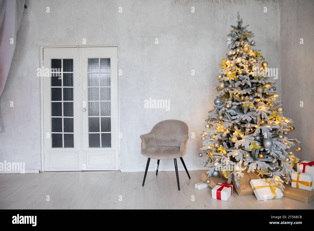 Decorated Christmas tree with gifts in white room interior Stock Photo ...