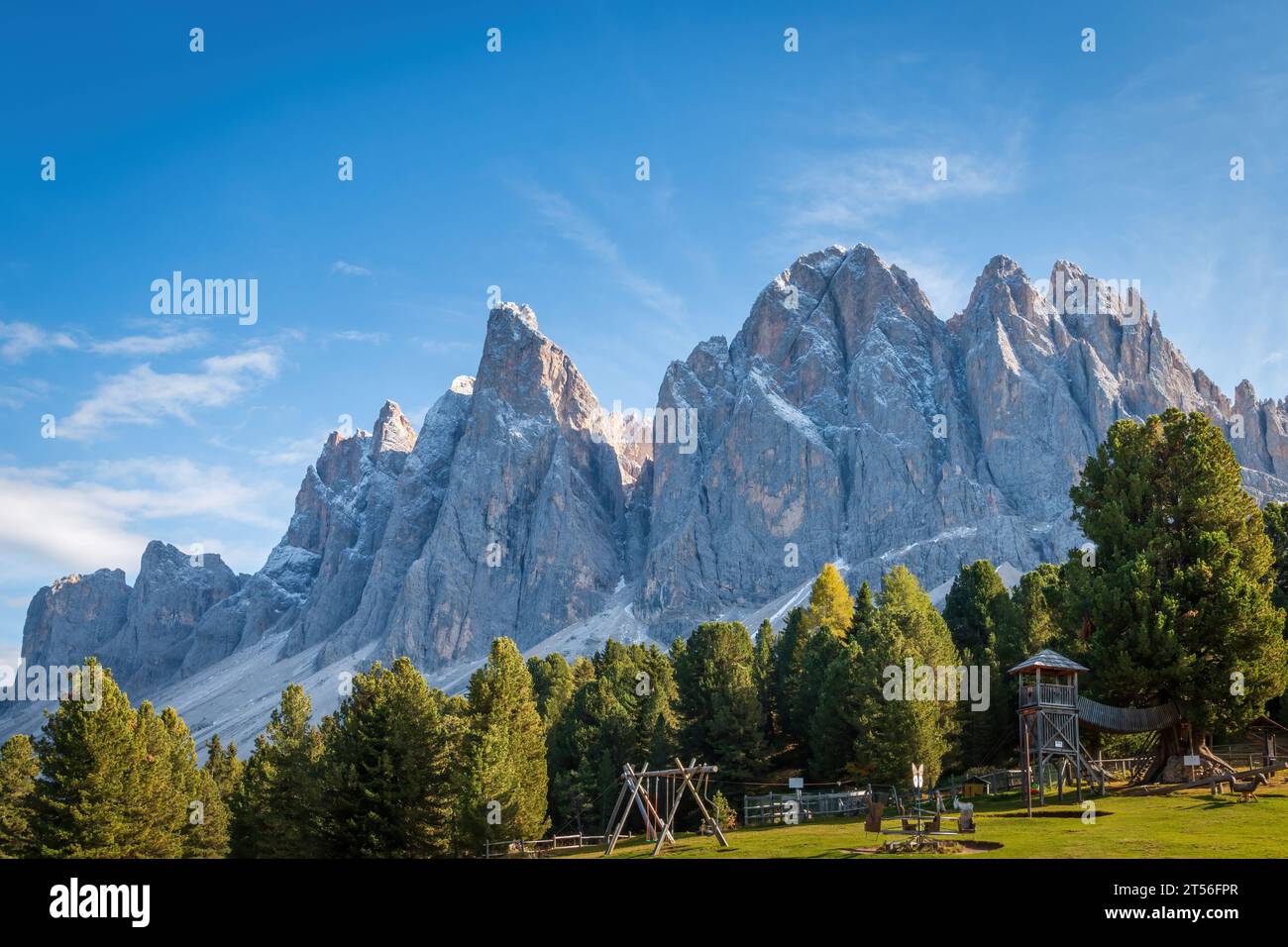 Scenic view of La Furchetta and Sass Rigais mountains, Dolomites, South Tyrol, Italy in the background of a playground against blue sky Stock Photo