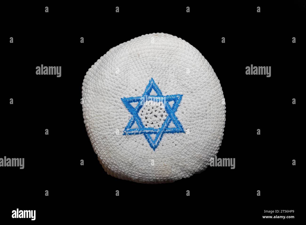 A knitted version of the kippa, small circular headgear of the Jews with a blue Star of David, hexagram, on a white background, studio photograph Stock Photo