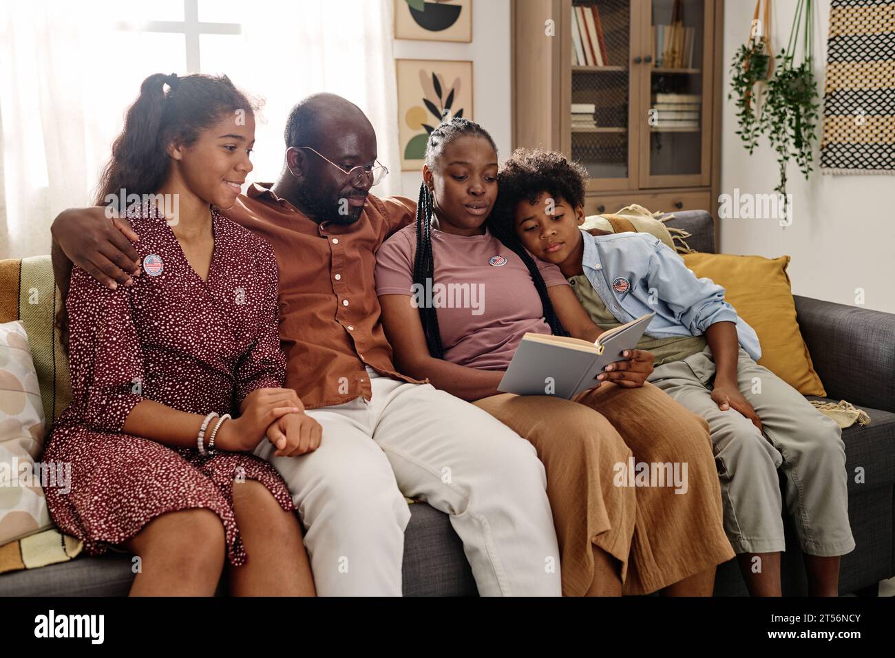 Hugging Black family sitting on couch and reading book about Martin ...