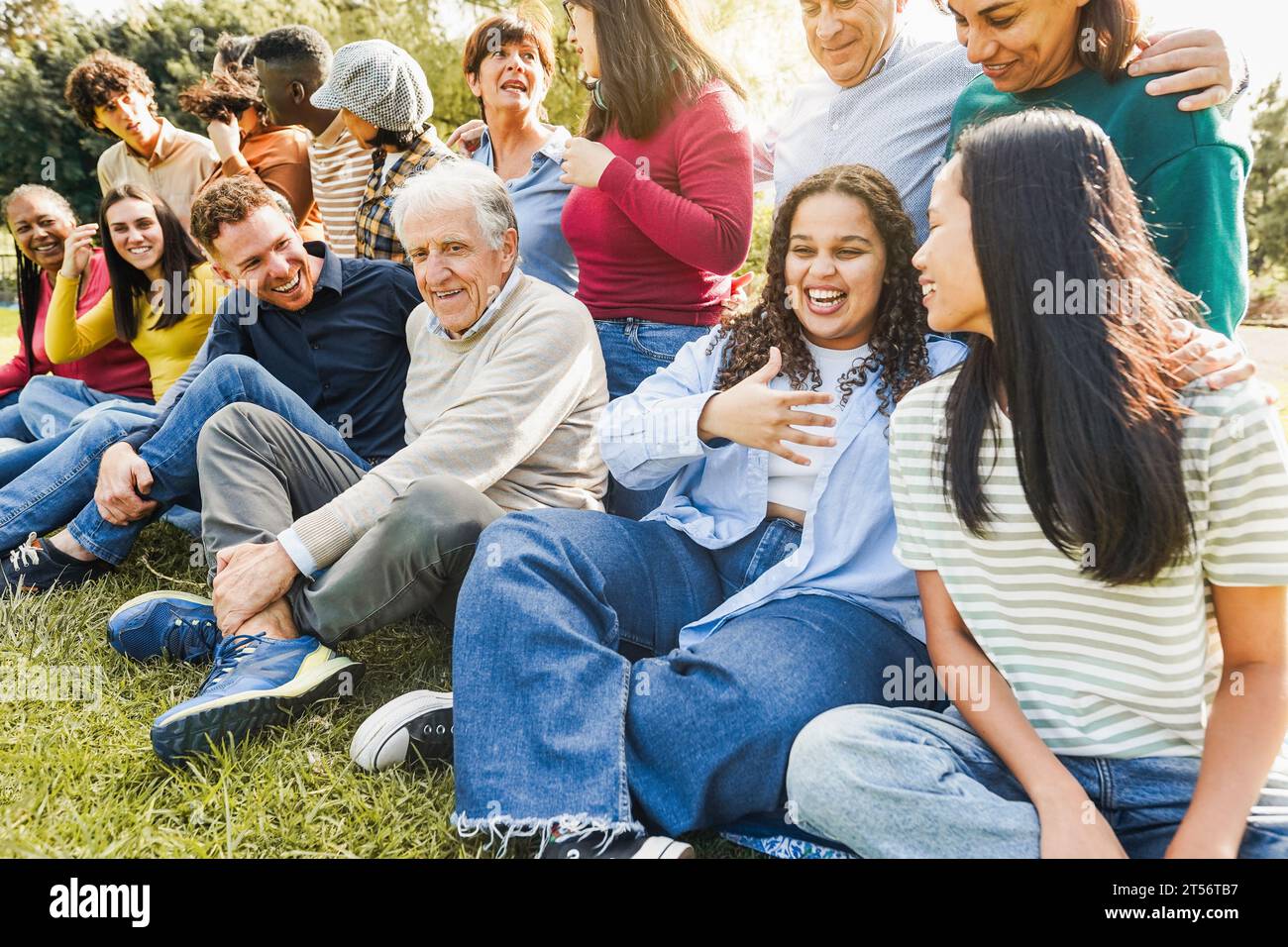 Group of multigenerational people smiling in front of camera - Multiracial friends of different ages having fun together - Main focus on senior man wi Stock Photo