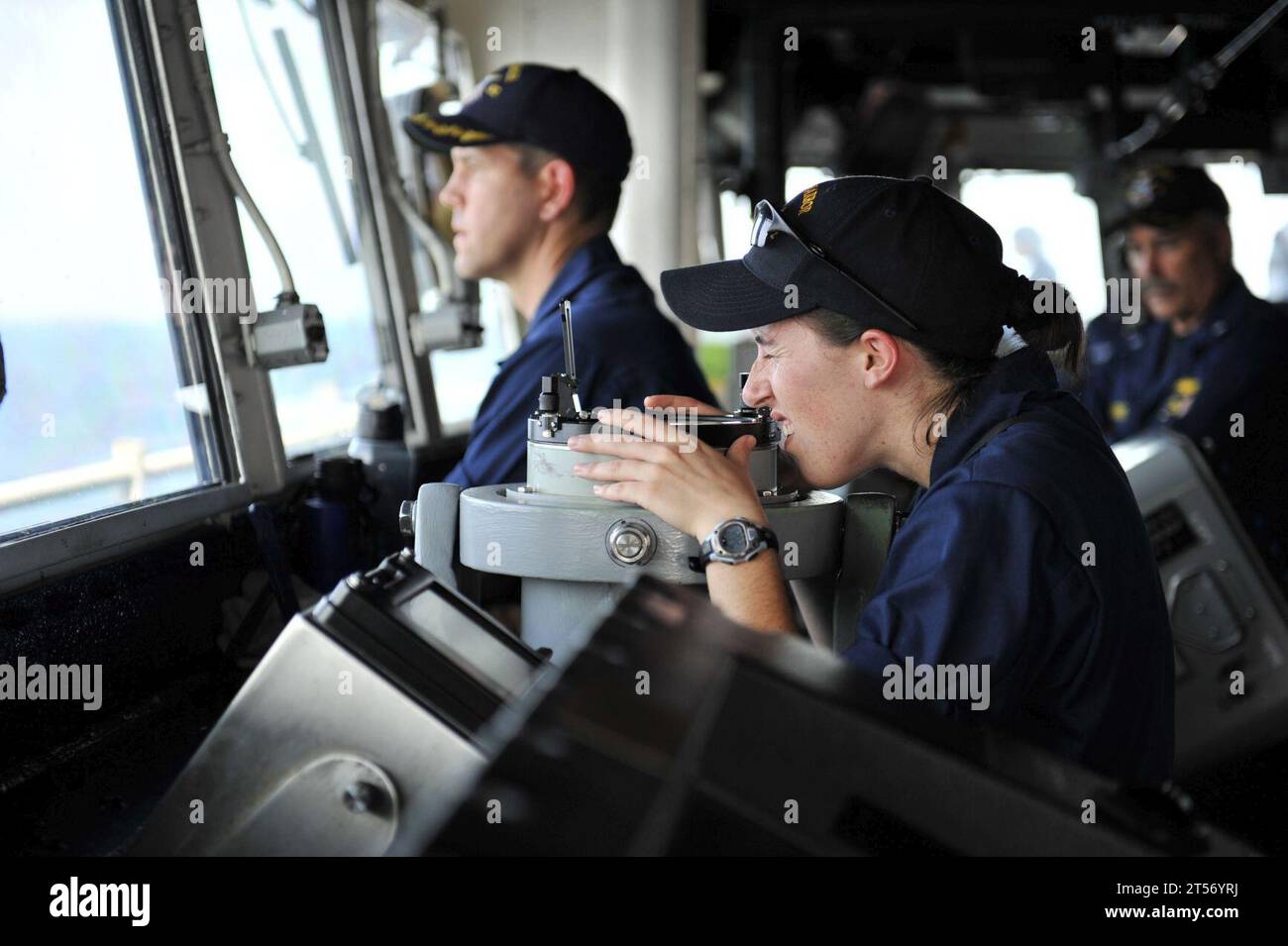 US Navy A Sailor looks through a telescopic alidade in the pilothouse.jpg Stock Photo