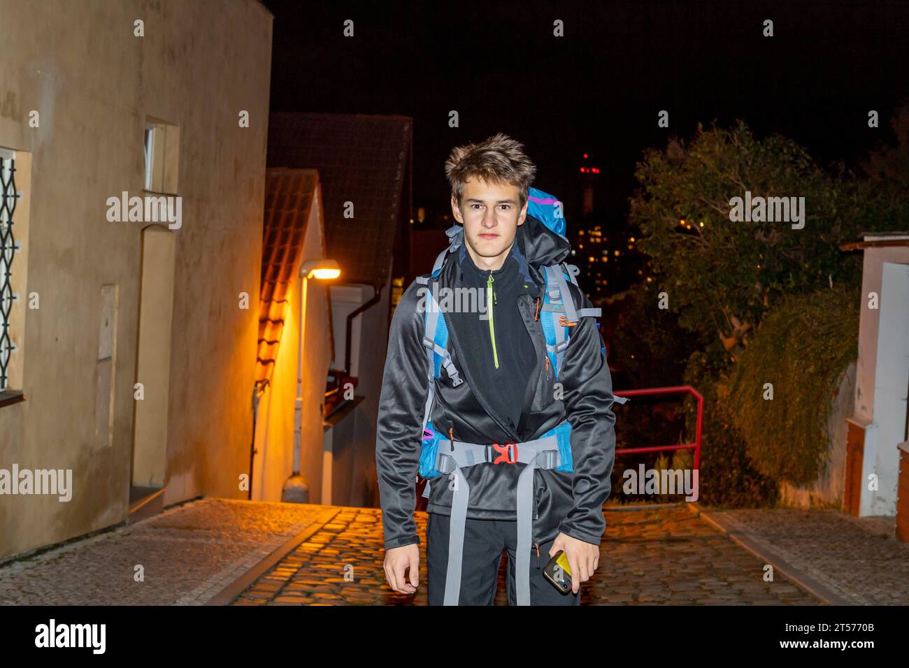 blond boy-teenager starting out on the trip in the night with rucksack and mobile phone Stock Photo