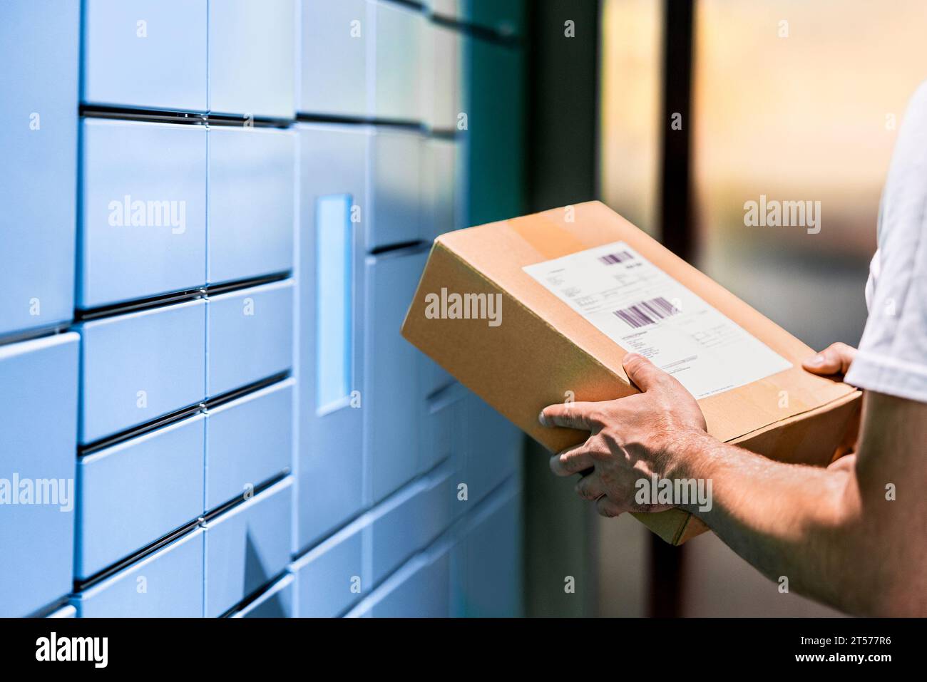 Parcel locker and package delivery service machine. Collect packet at mail storage station at post office. Man holding a box in hand. Stock Photo