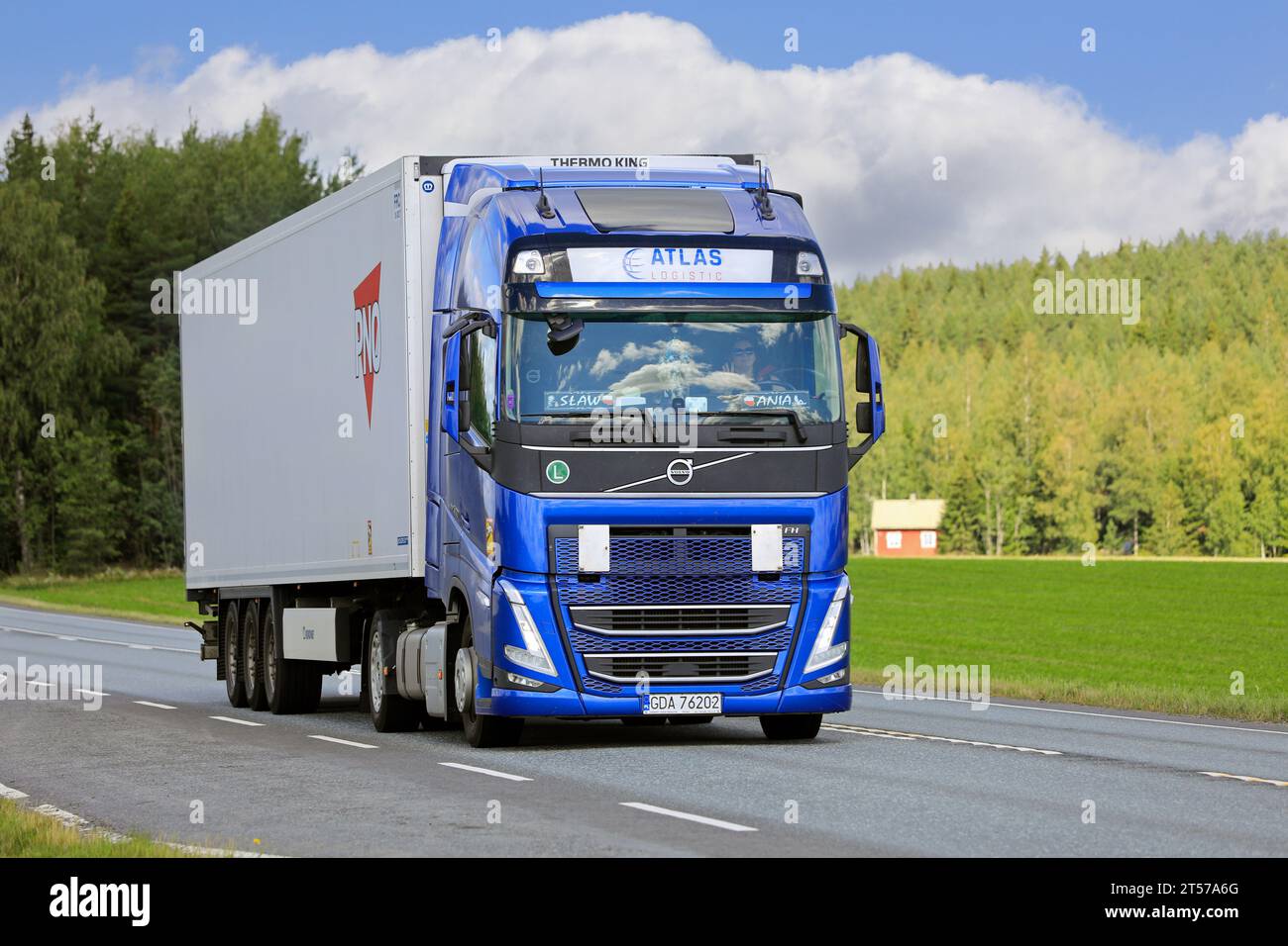 New blue Volvo FH 500 truck Atlas Logistic in front of refrigerated semi-trailer moving on highway. Jokioinen, Finland. July 21, 2023. Stock Photo