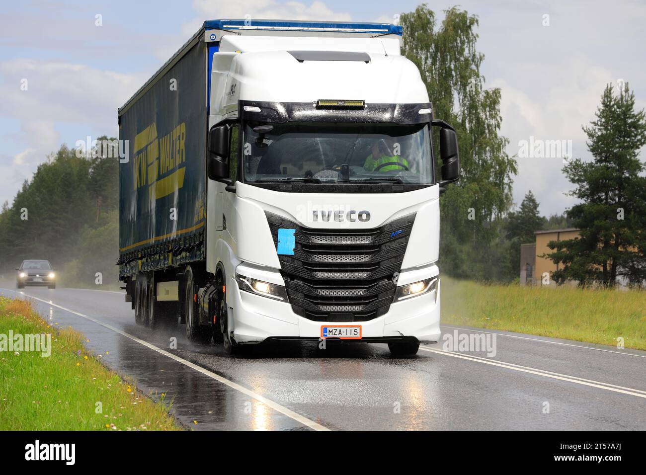 New, white gas-powered Iveco S-Way Natural Power, NP, truck in front of semi trailer in highway  traffic on a rainy day. Salo, Finland. July 20, 2023. Stock Photo
