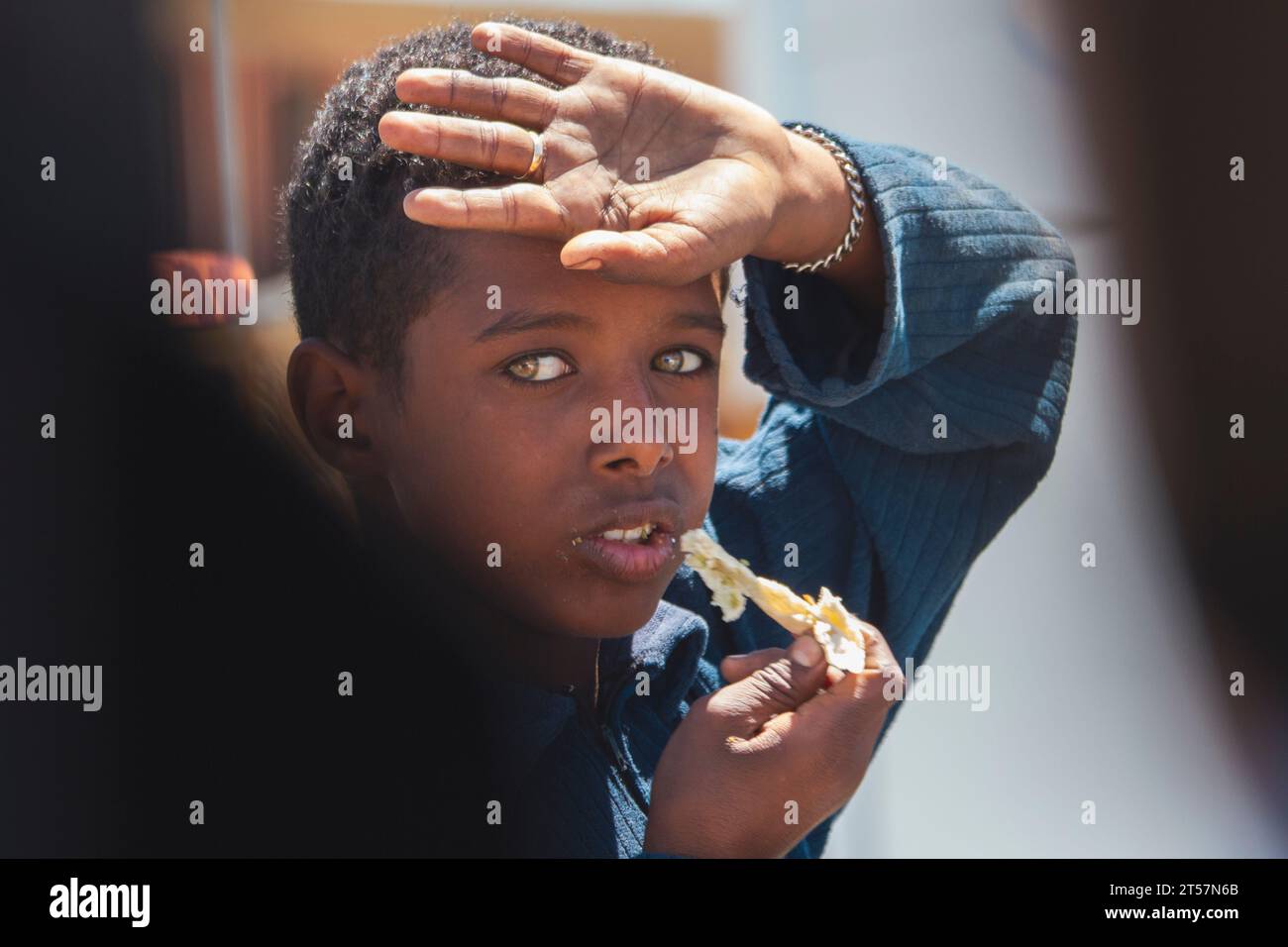 Arabian boy with beautiful eyes eats bread,20.04.2012 Qesm Al Qoseir Stock Photo