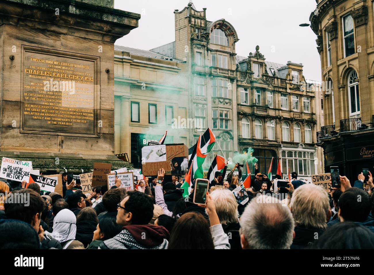 Crowd wave Palestine flags, green smoke bombs and handmade protest signs at Grey's Monument. Newcastle Upon Tyne, England, UK - Oct 28 2023. Stock Photo