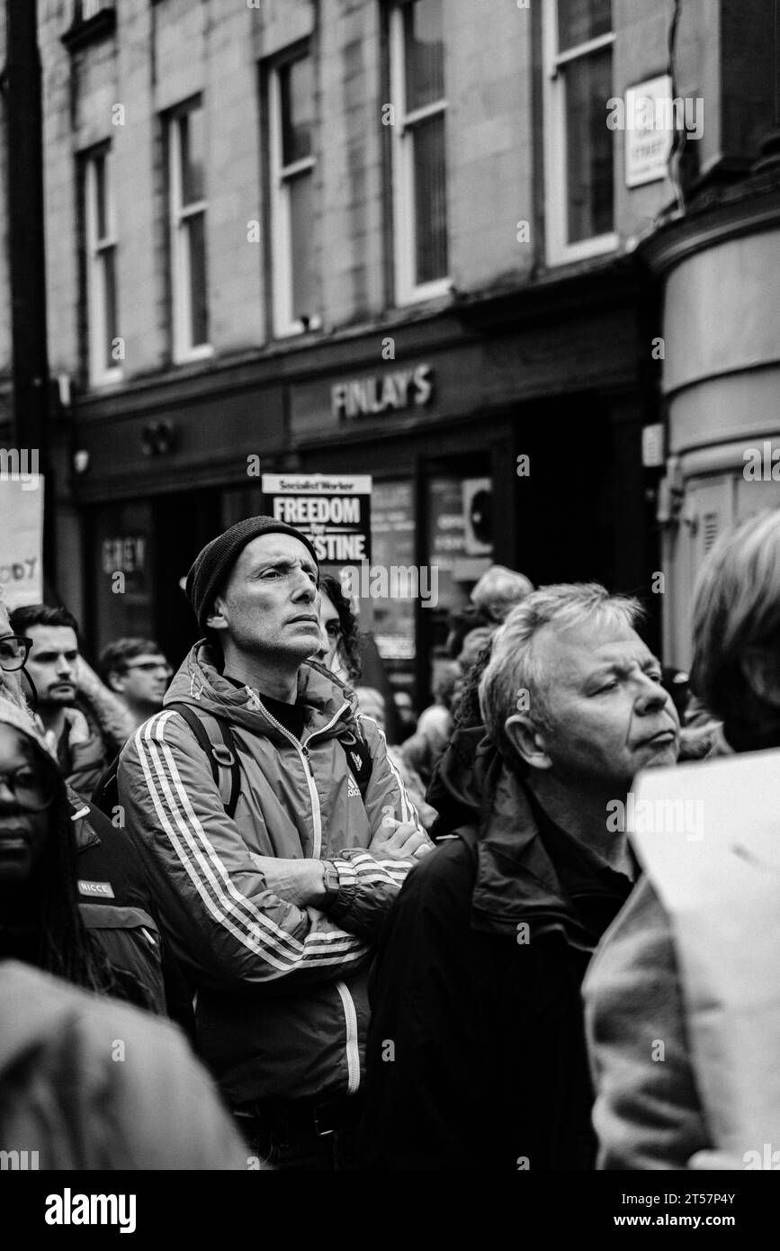 Man in crowd of protesters wearing Adidas jacket and hat at pro-Palestine march, Grey Street. Black and white. Newcastle Upon Tyne, UK - Oct 28 2023 Stock Photo