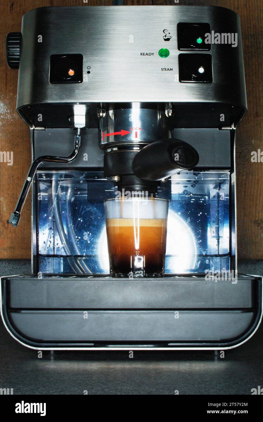 Espresso shot pouring from countertop espresso machine. Stock Photo