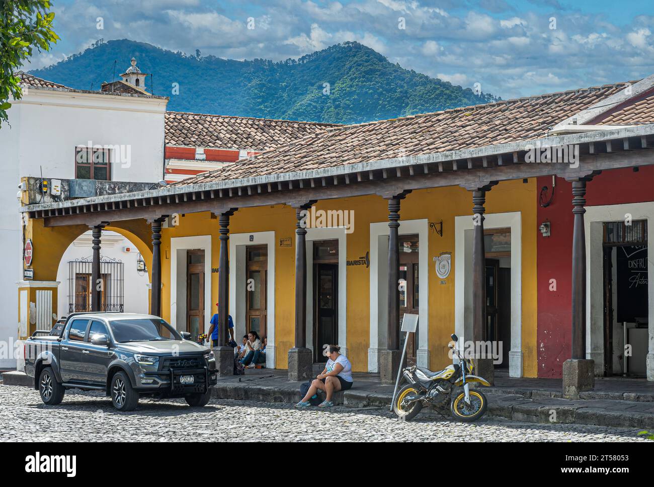 Guatemala, La Antigua - July 20, 2023: People, cars and motorbike in front of Cafe Barista restaurant and bistro on NW corner of Plaza Mayor, central Stock Photo