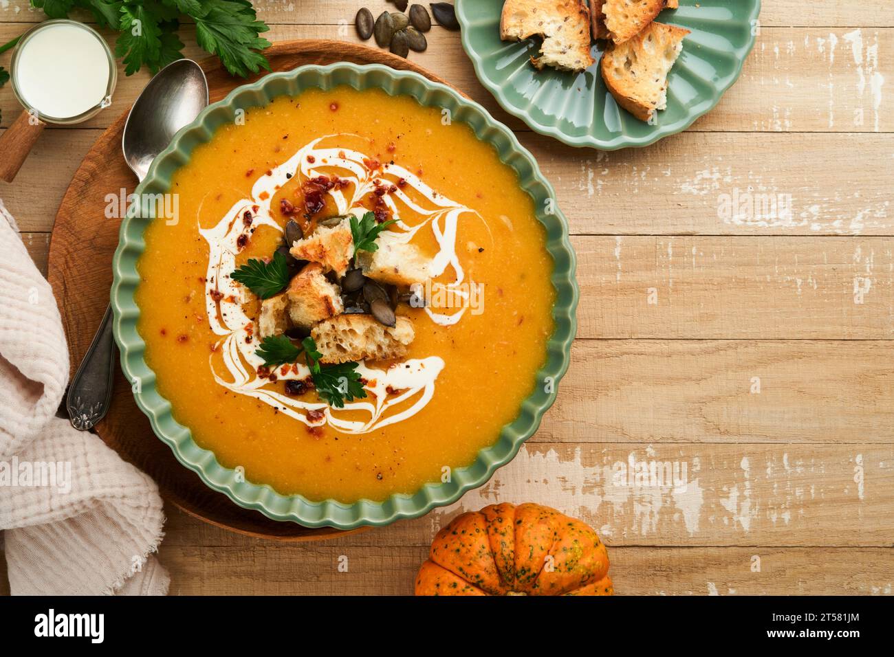 Pumpkin and carrot cream soup with herbs, seasonings and seeds in bowl on old wooden background in rustic style. Thanksgiving traditional autumn pumpk Stock Photo