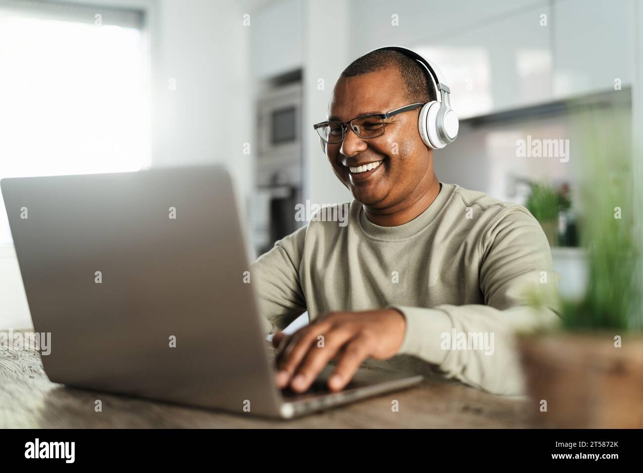Happy mature Latin man using laptop at home - Technology and smart working concept Stock Photo