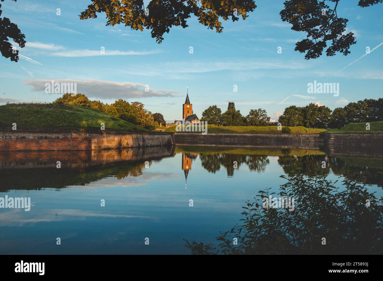 Morning sun illuminates the church and lake around the town of Naarden in the central part of the Netherlands. A historical landmark. Sunrise glow. Stock Photo