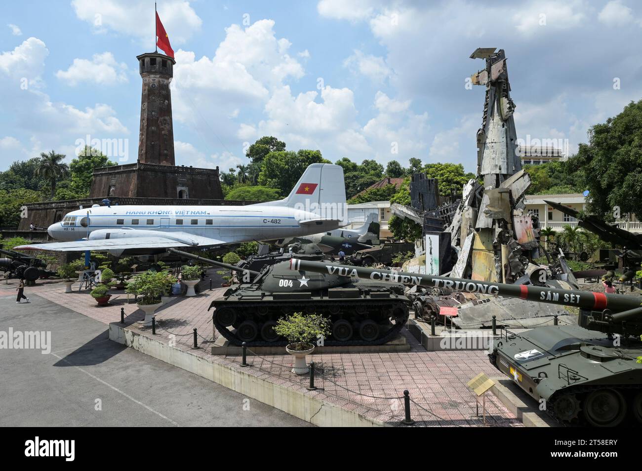 VIETNAM, Hanoi, Military Museum, military equipment and war scrap from french colonial war 1946-1954 and the US american war in Vietnam 1955 – 1975, US battle tank M-48 Patton, US M107 175MM self-propelled howitzer, vietnamese airplane and wreckage of Grumman F6F Hellcat an American carrier-based fighter aircraft used by the french colonial army, shot down at battle in Dien Bien Phu 1954, behind flag tower / VIETNAM, Hanoi, Militär Museum, Ausstellung mit Rüstung und Waffen zu den Kriegen der Franzosen und Amerikaner in Vietnam, hinten Flaggenturm der alten kaiserlichen Festung Stock Photo