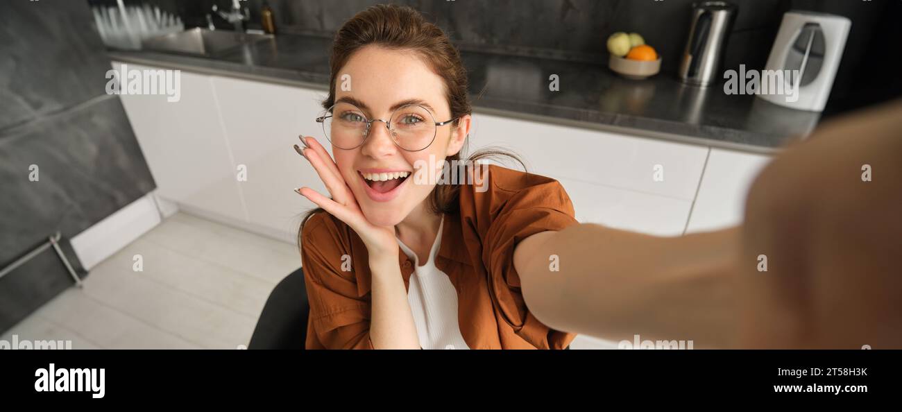 Portrait of carefree young woman in glasses, taking selfie from home ...