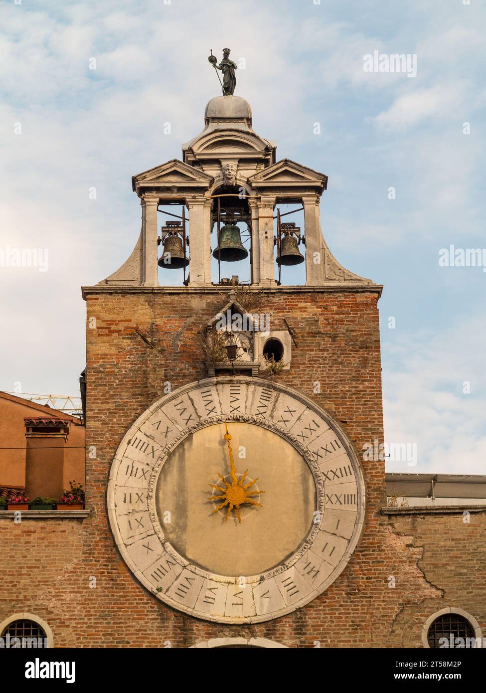 Bell tower of a church with three bells, decorated with a clock with Roman numerals in Venice, Italy. Stock Photo