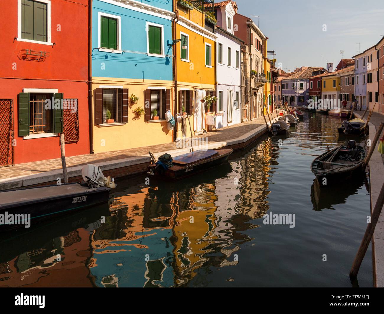 Colorful houses of Burano in Italy along a canal where motorboats are moored. Stock Photo