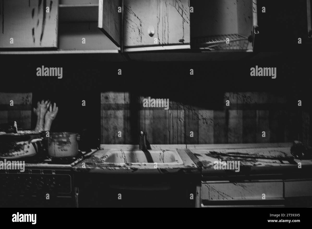 Horror room, kitchen in splashes of blood and hands in a pan on the stove in the kitchen in the dark, black and white photo, room of a maniac and kill Stock Photo