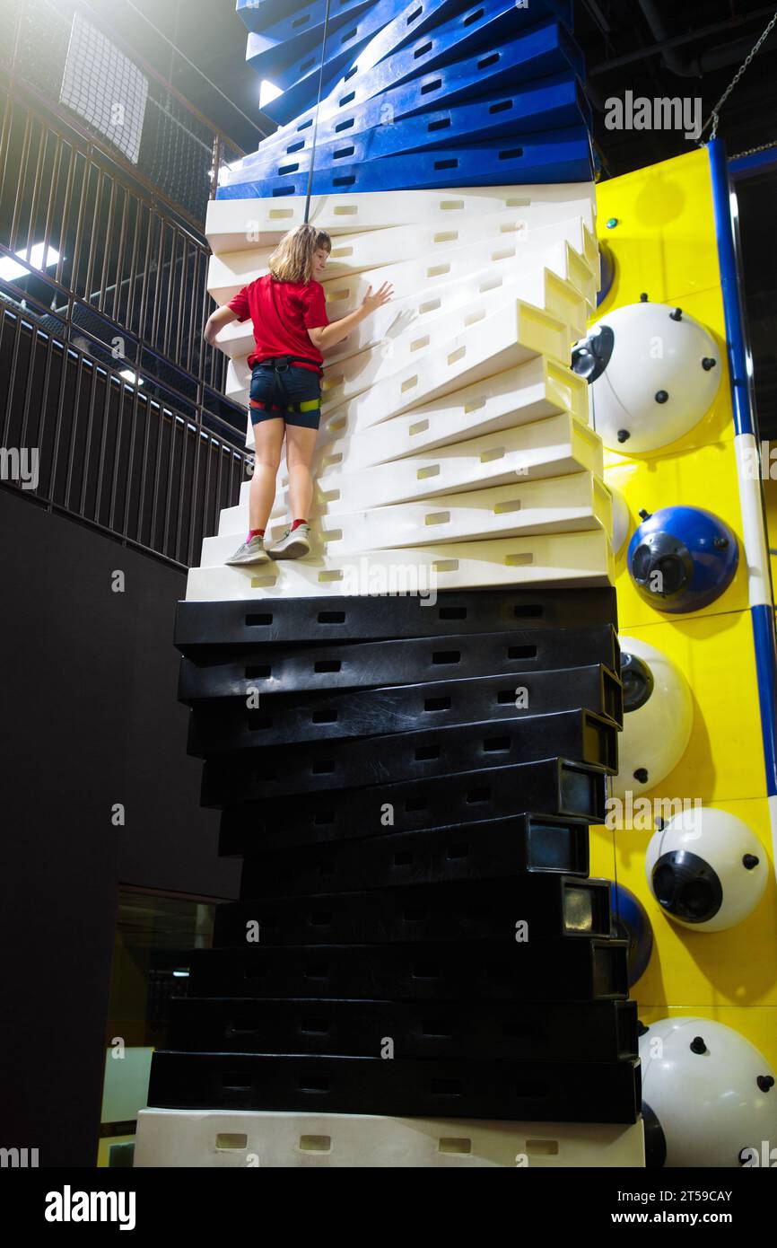 Child climbing in amusement park. Bouldering fun on kids birthday party. Indoor playground with climb wall. Healthy activity for children. Stock Photo
