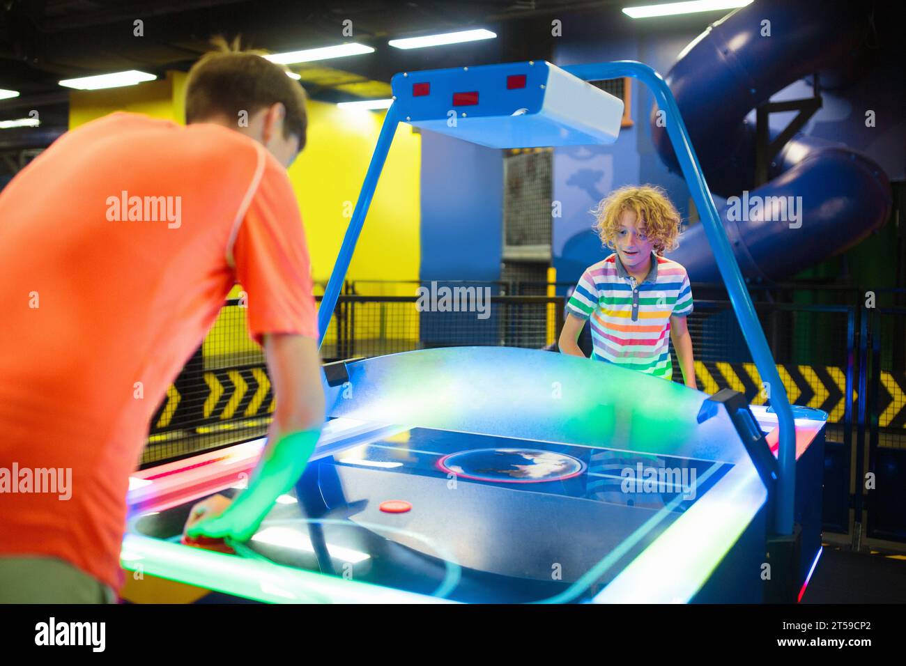 Kids play air hockey. Fun arcade games. Child at amusement park. Family