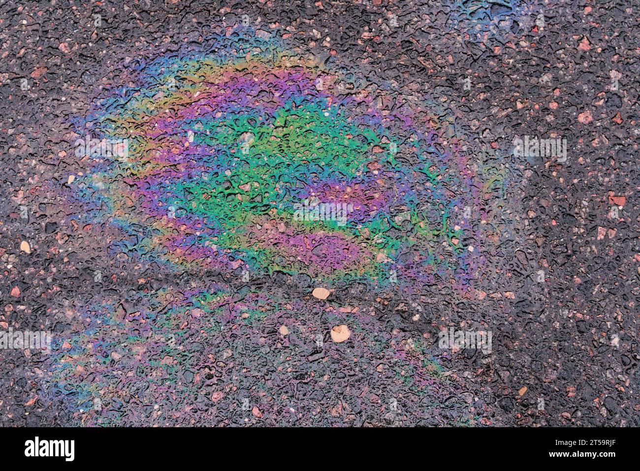 Fuel stain on wet asphalt. Colored stains from a gasoline leak on the