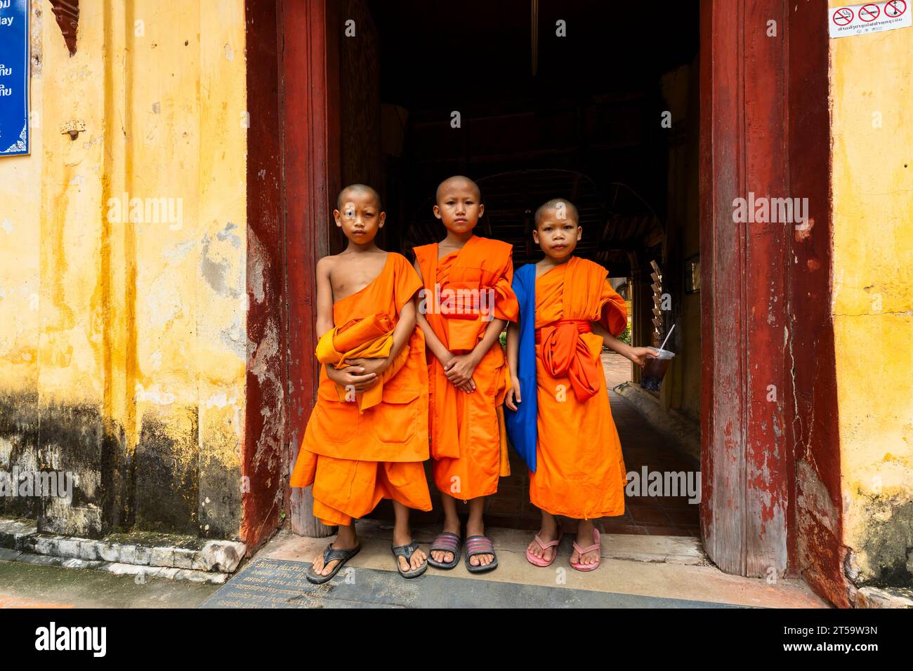 Little monks with orange robes at gate, Wat Si Saket(Wat Sisaket), Vientiane, Laos, Southeast Asia, Asia Stock Photo