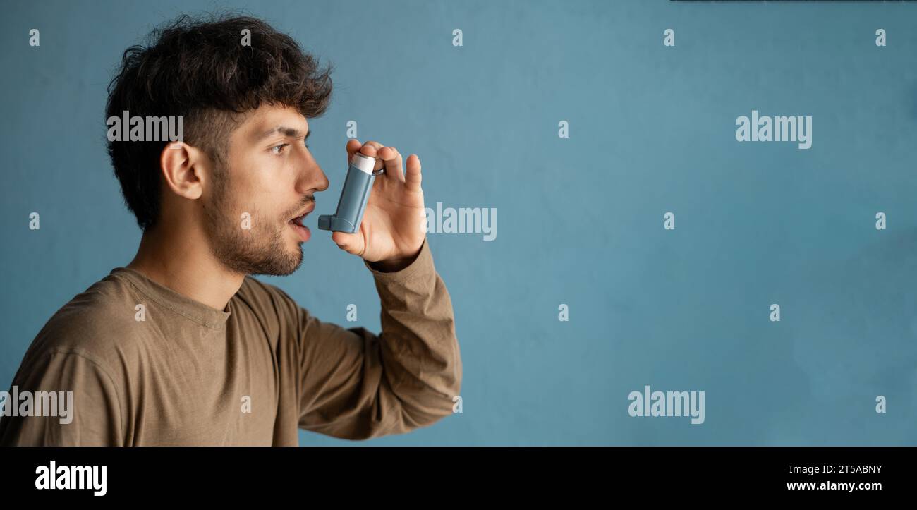 portrait of arabic young man using asthma inhaler against blue ...