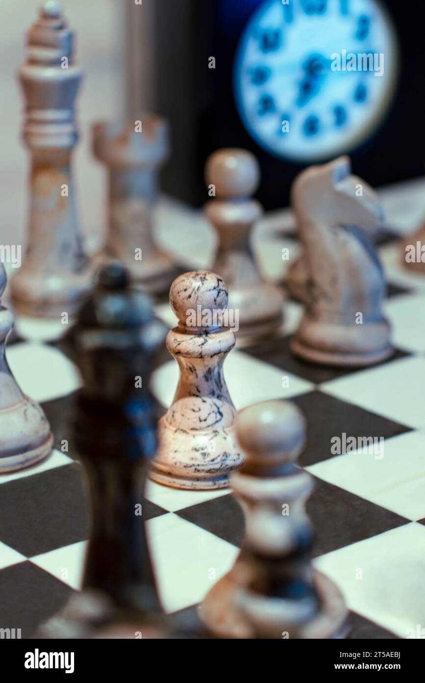 A chessboard and white and black chess pieces for playing chess. There are sixteen pieces of each color: one king, one queen, two rooks, two bishops, Stock Photo