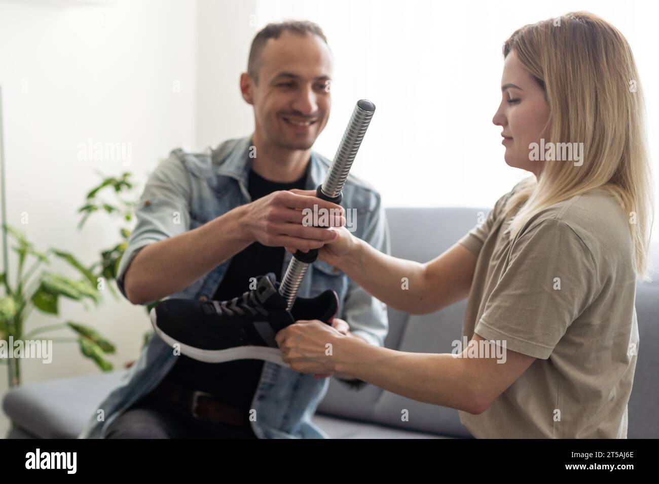 Modern Hospital Physical Therapy: Helps Disabled Patient Wearing Advanced Robotic Legs. Physiotherapy Rehabilitation Technology Stock Photo