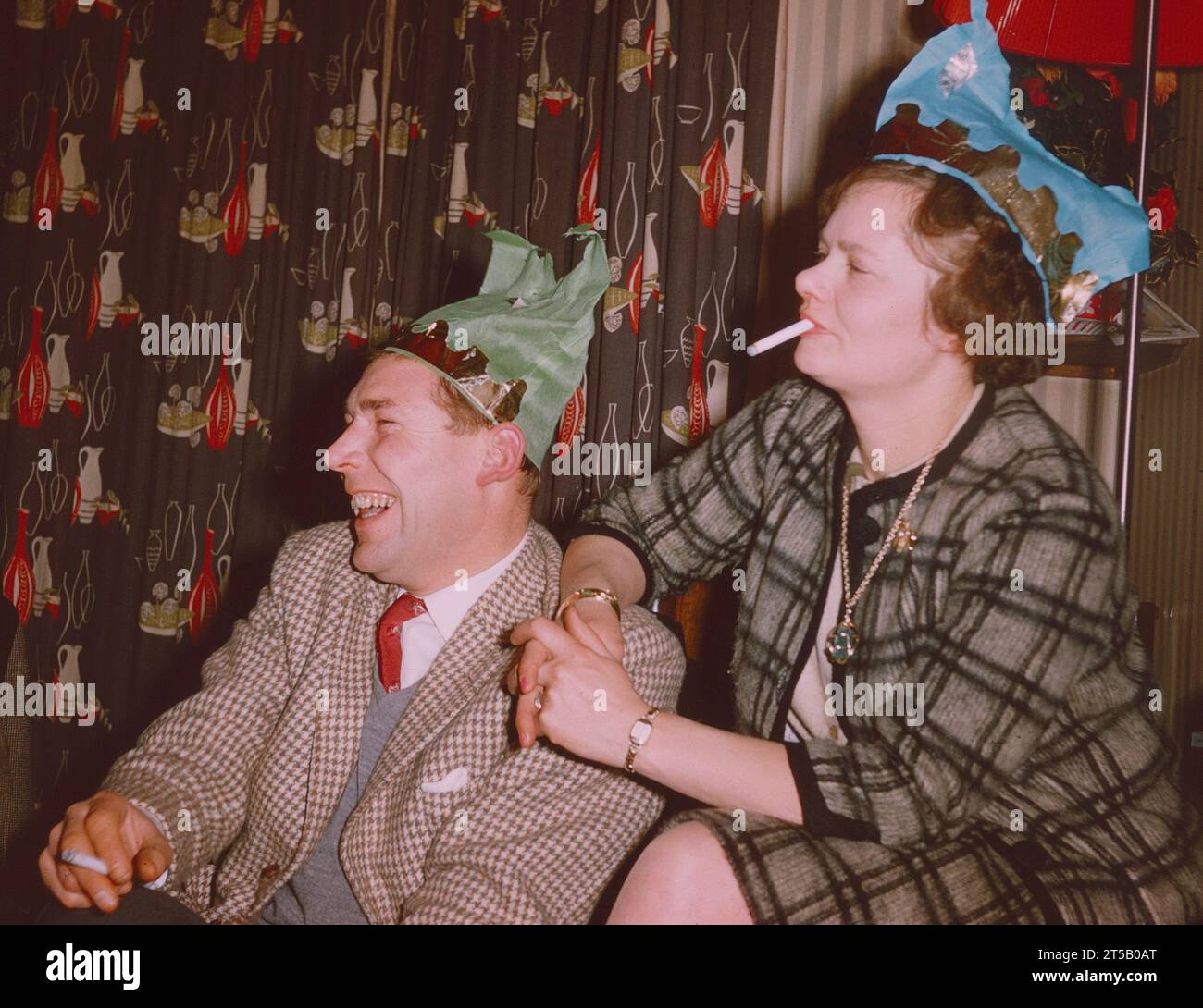 Man laughing and woman enjoying a joke at a Christmas party Scotland 1960s, both smoking Stock Photo