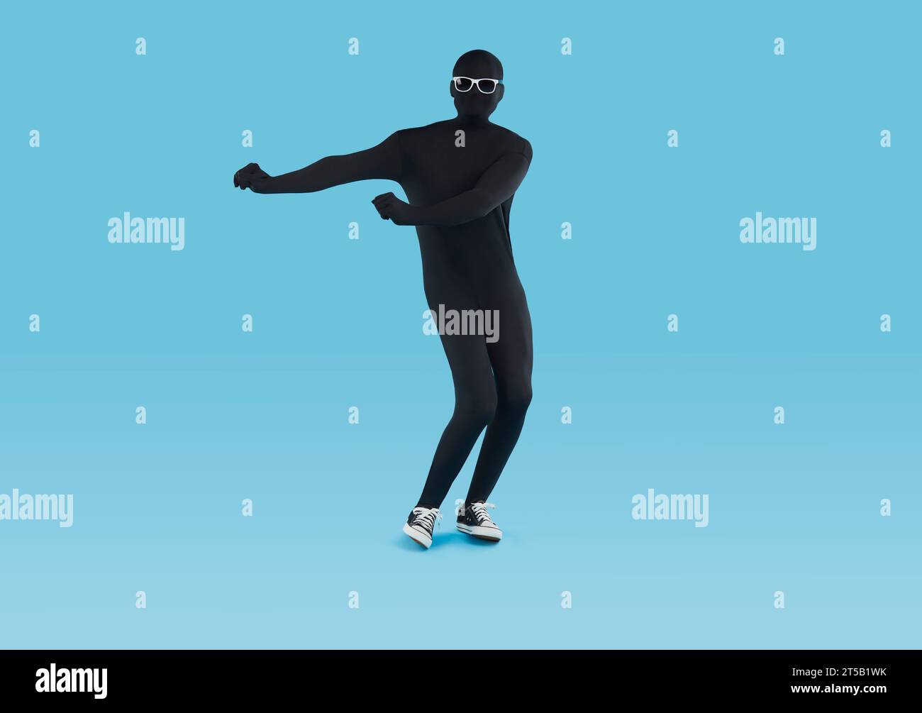 Funny happy man in black spandex bodysuit and glasses dancing isolated on blue background Stock Photo