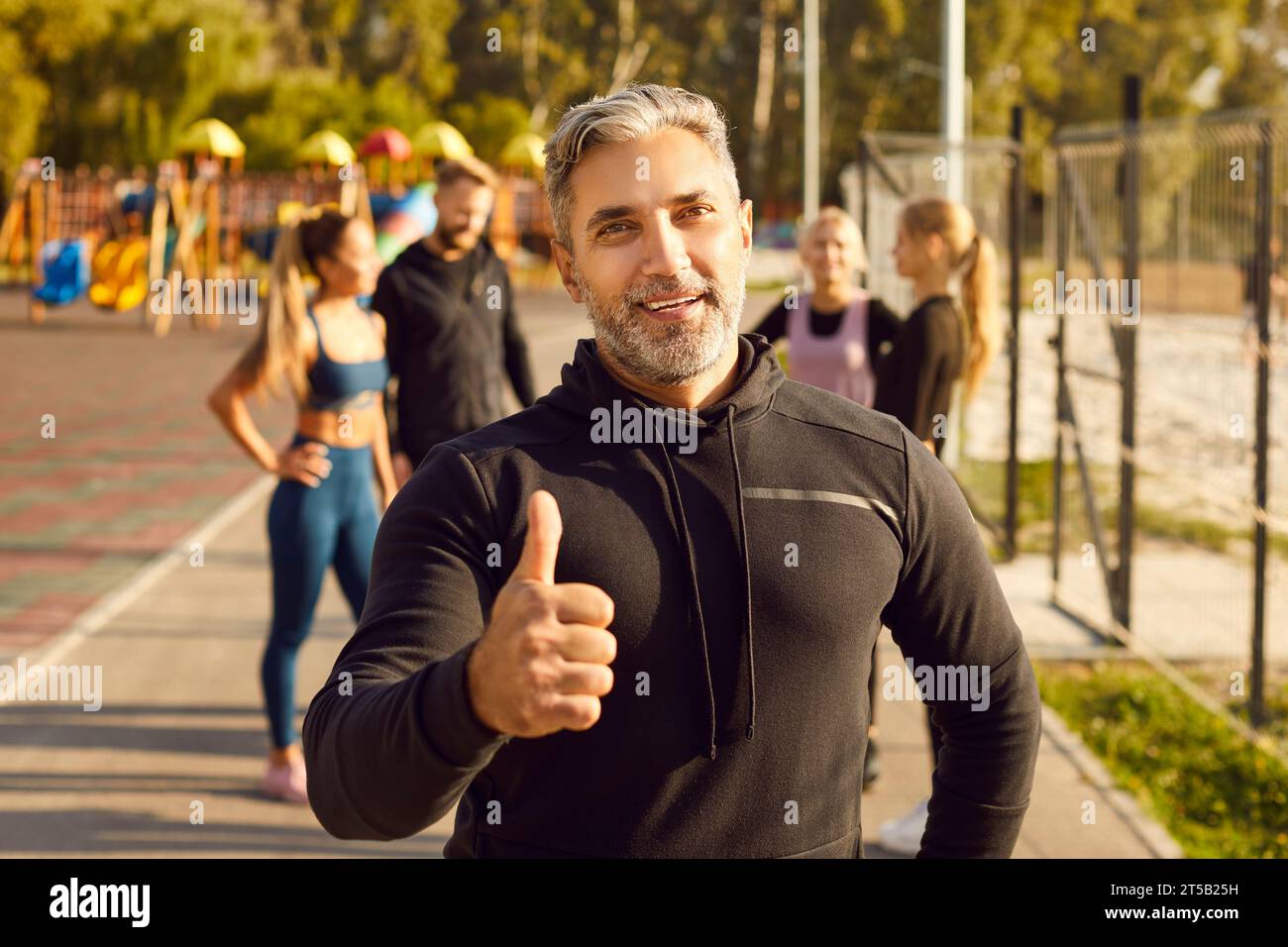 Happy man looking at camera showing thumb up sign after sport fit exercises in the park in nature. Stock Photo