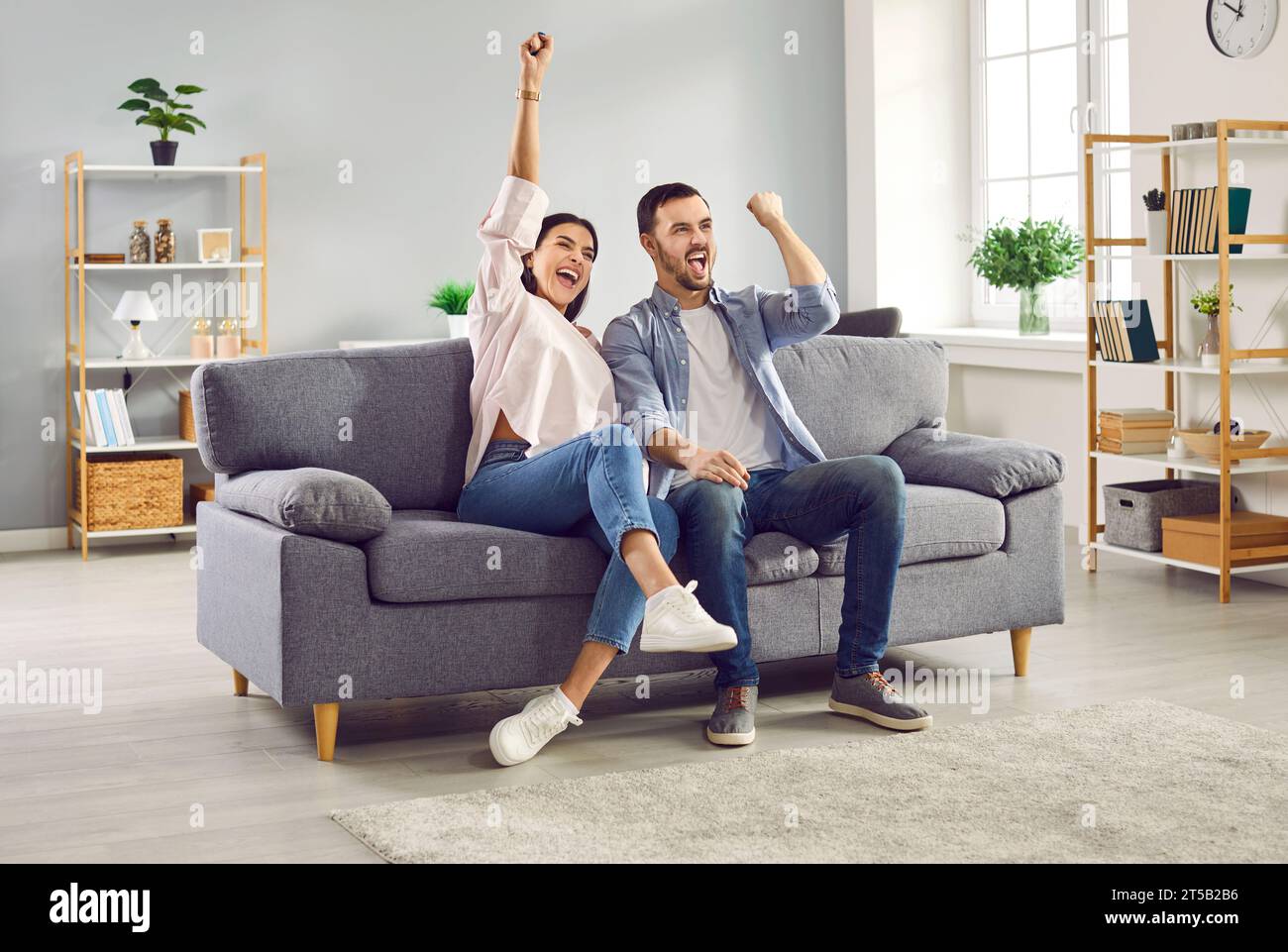 Excited couple watching football or hockey match together at home Stock Photo