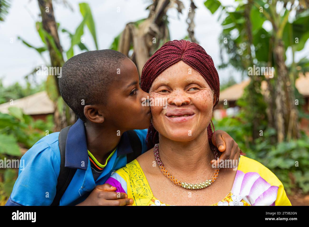 Little child from back to school gives her mom a kiss on the cheek outside. Stock Photo